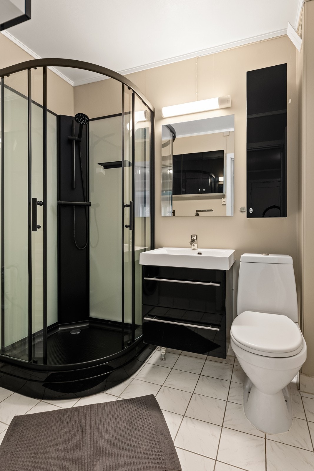 Badet er utstyrt med servantinnredning, toalett og et moderne dusjkabinett. Galleribilde