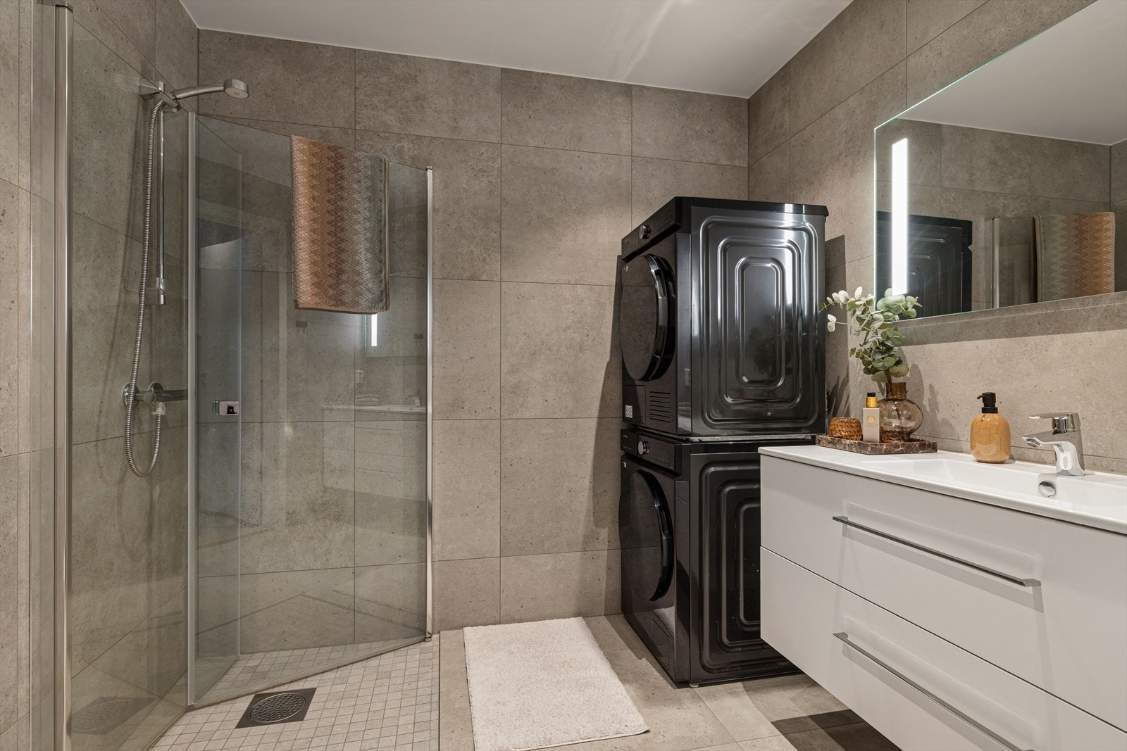 Lekkert og moderne bad med dusjhjørne og opplegg for vaskemaskin og tørketrommel. Galleribilde