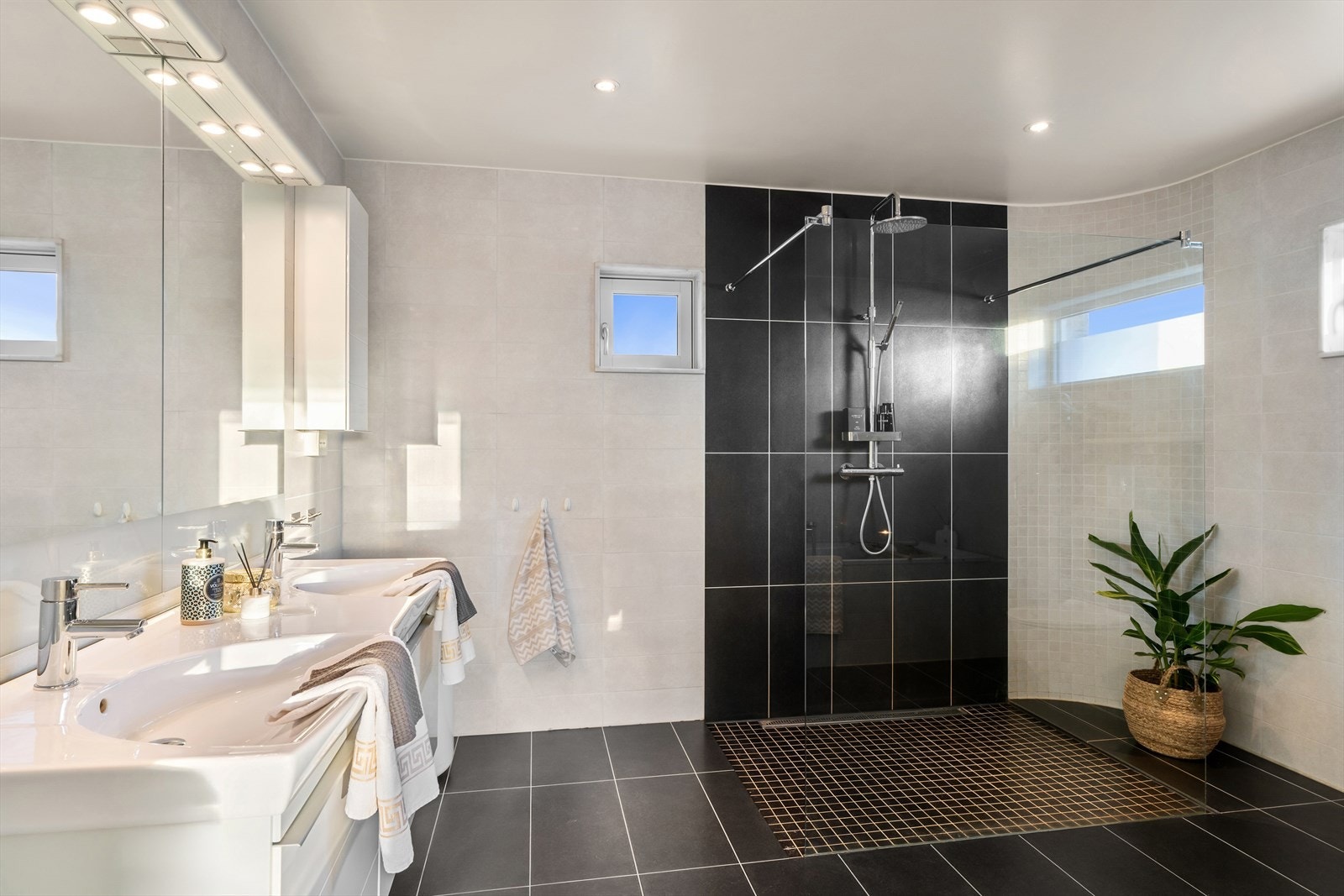 Helfliset bad med dusjnisje med mosaikkfliser og unidrain, innfelt badekar, vegghengt WC og dobbel servant Galleribilde