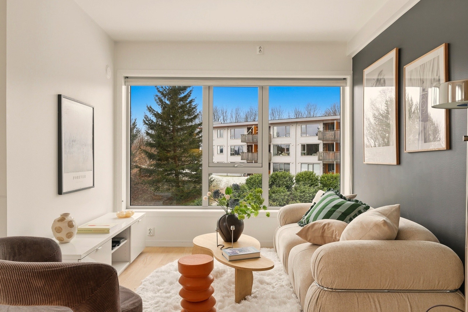 Stue med store vindusflater, lysmalte overflater og parkettgulv i ask - et lyst og trivelig oppholdsrom. Galleribilde