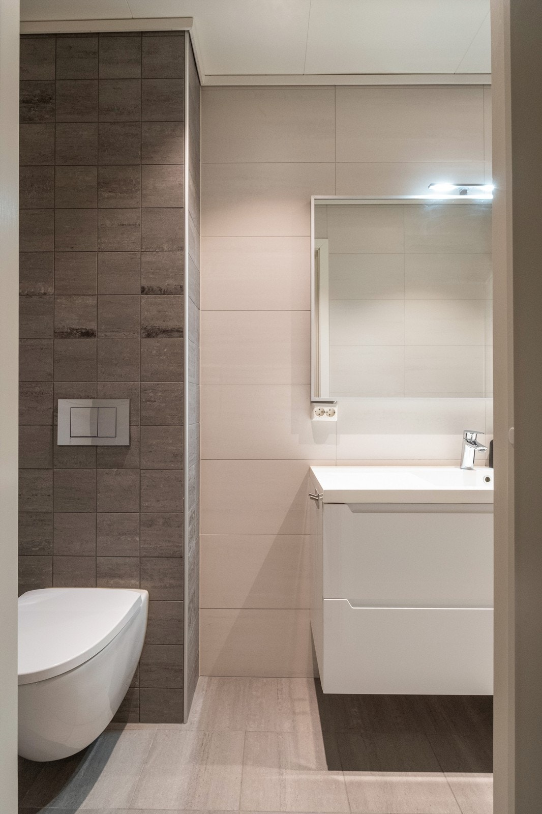 Badet er utstyrt med vegghengt toalett og moderne baderomsinnredning med heldekkende vask. Galleribilde