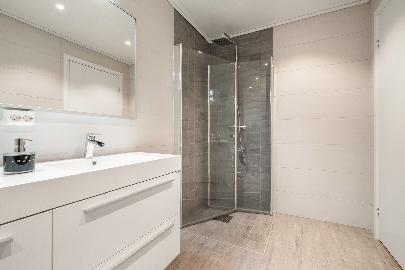 Dusj med glassdører og tropedusj kompletterer rommets funksjonelle design. Galleribilde