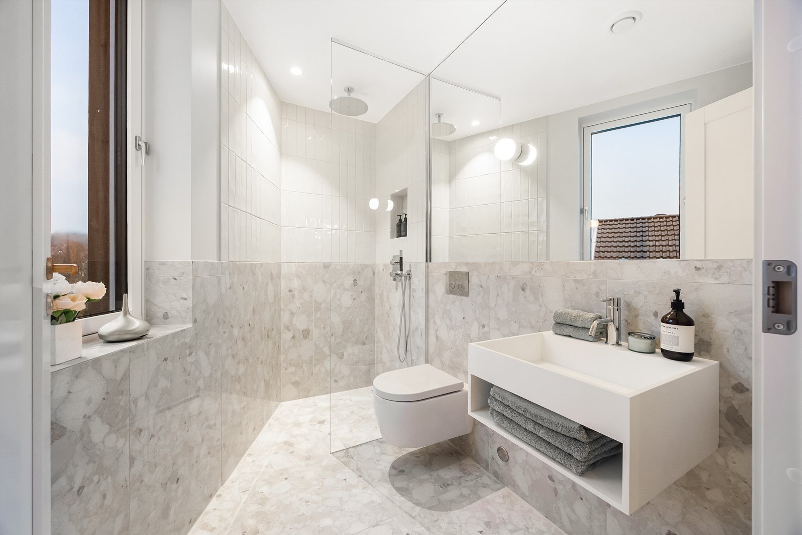 Suite bad ment for hovedsoverommet, flislagt med varme i gulv, vegghengt servant og toalett, veggspeil Galleribilde