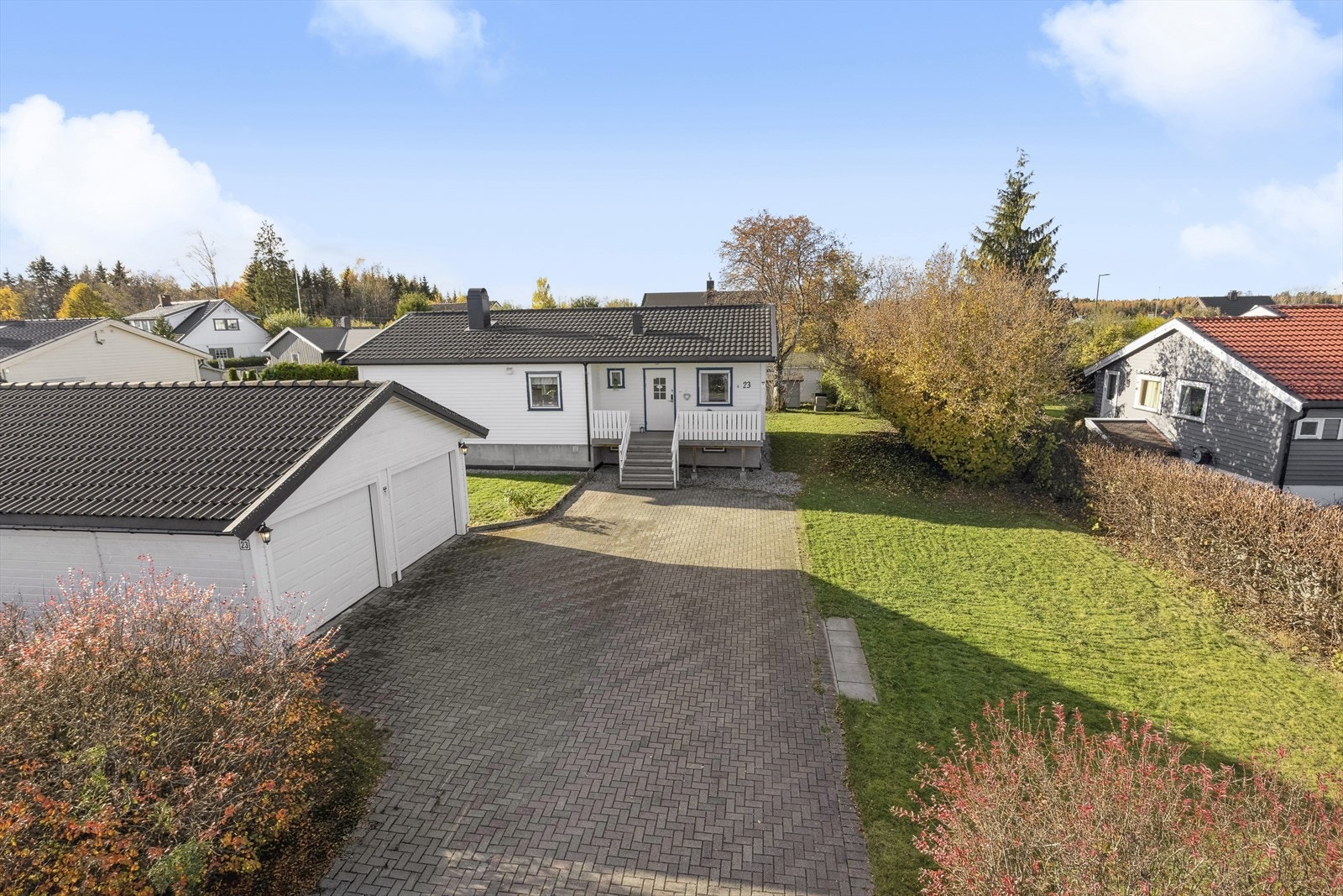 Eiendommen har en dobbelgarasje og steinlagt gårdsplass med biloppstillingsplass for flere biler. Galleribilde