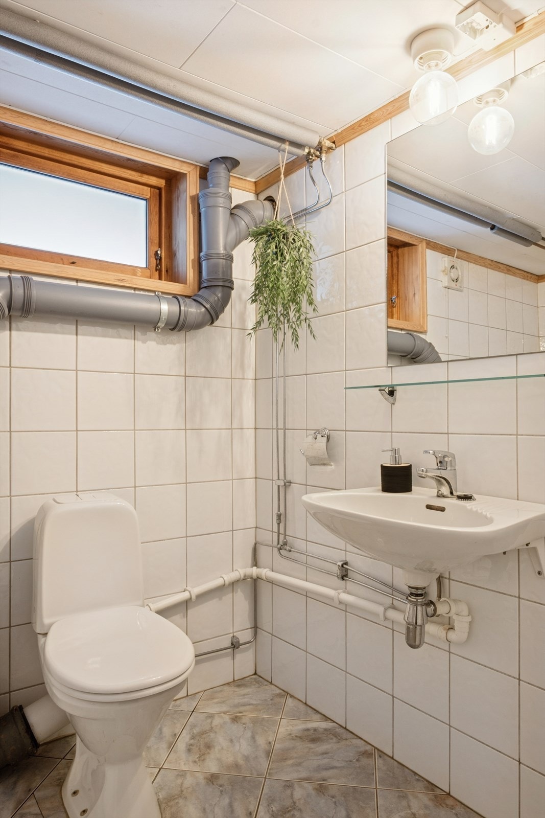 Badet er innredet med en vegghengt servant, frittstående toalett og et badekar. Galleribilde