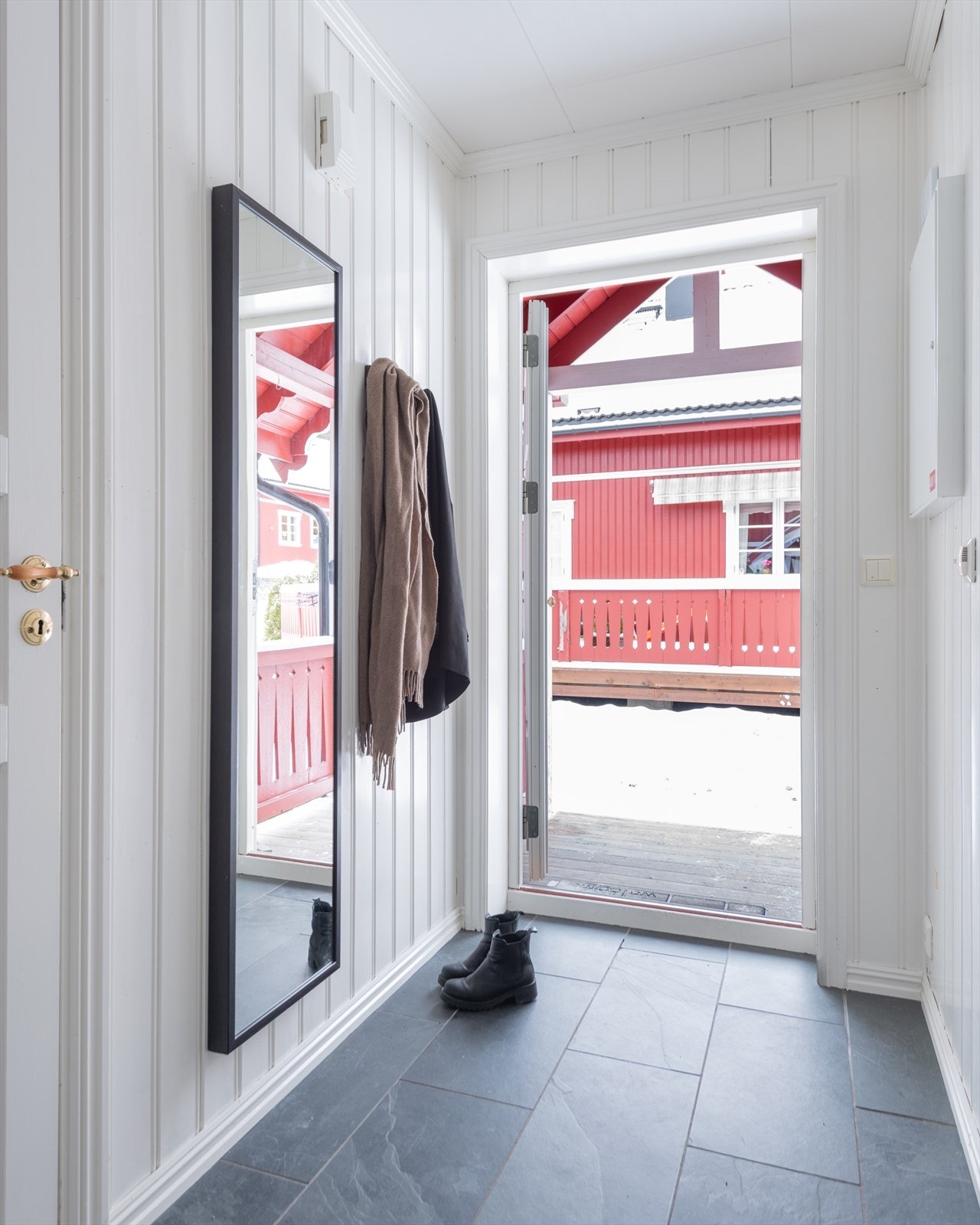 Velkommen inn! Entréen har lun varme under grå gulvfliser og lysmalt panel på veggene. Galleribilde