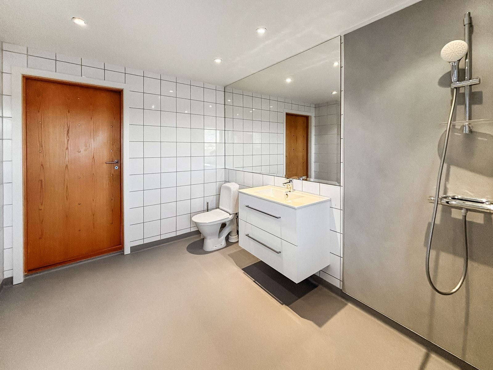 Romslig bad med nytt utstyr/innredning fra 2025 bestående av servant med underskap, speil, dusjdører, dusj og gulvmontert toalett Galleribilde