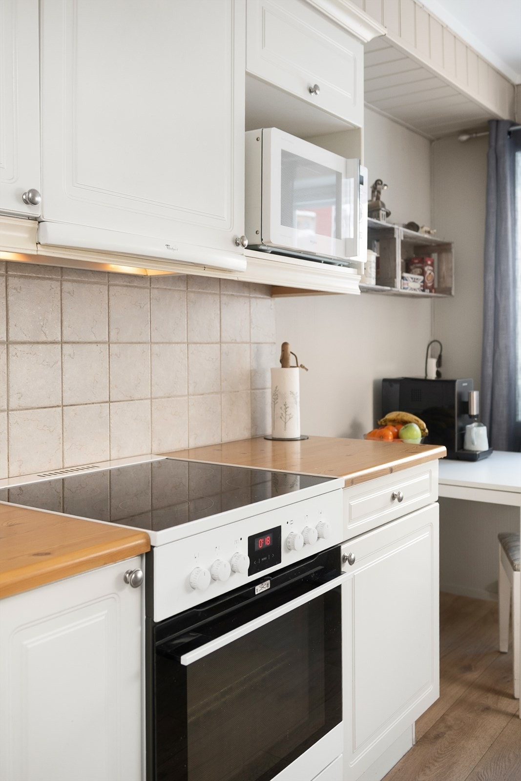 Det er fliser på veggen mellom over- og underskap, og plass til hvitevarer. Galleribilde