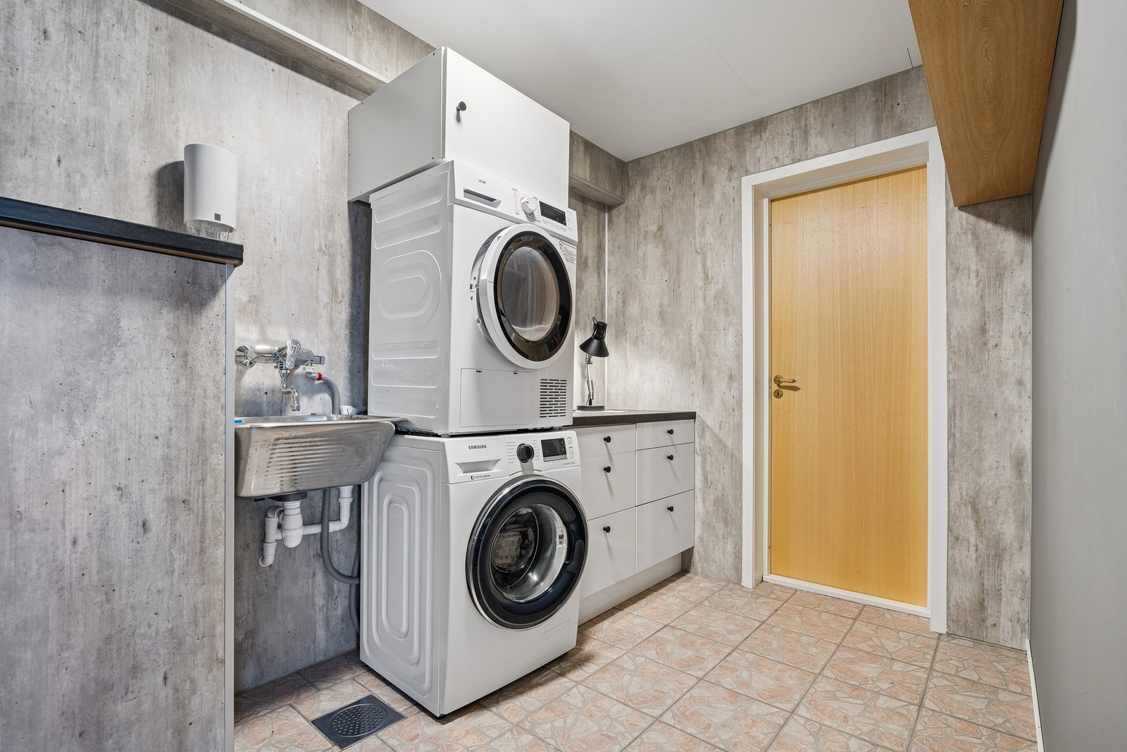 Separat vaskerom med utslagsvask, opplegg for vaskemaskin, enkel innredning og adkomst til boder og garasje. Galleribilde