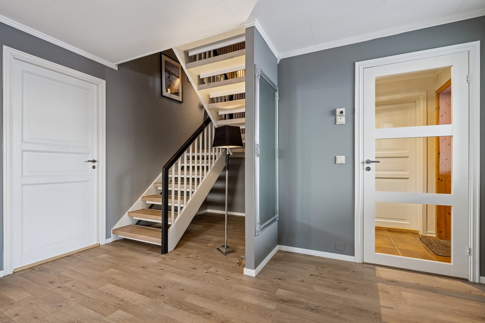 Velkommen inn! Det første man møter er en flislagt entre, med skyvedørsgarderobe. Herfra kan man ta seg videre til en stor hall, med tilgang på øvrige rom i etasjen, samt trapp opp. Galleribilde