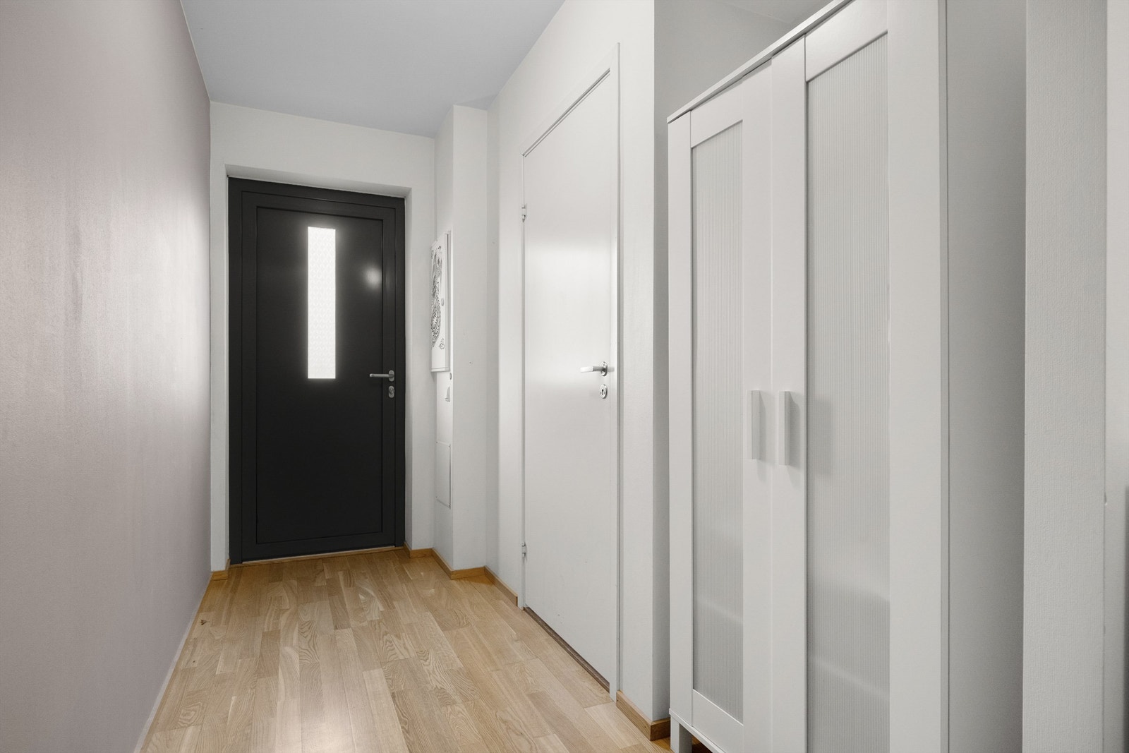 Velkommen inn i en lys entré med plass til oppbevaring av yttertøy.Fra gangen er det tilgang til bad og soverom på dette planet. Galleribilde