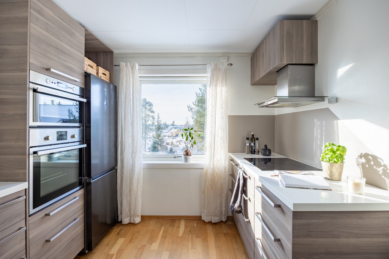 Kjøkkeninnredningen har slette fronter i hvit høyglans kombinert med laminert trefarge. Galleribilde