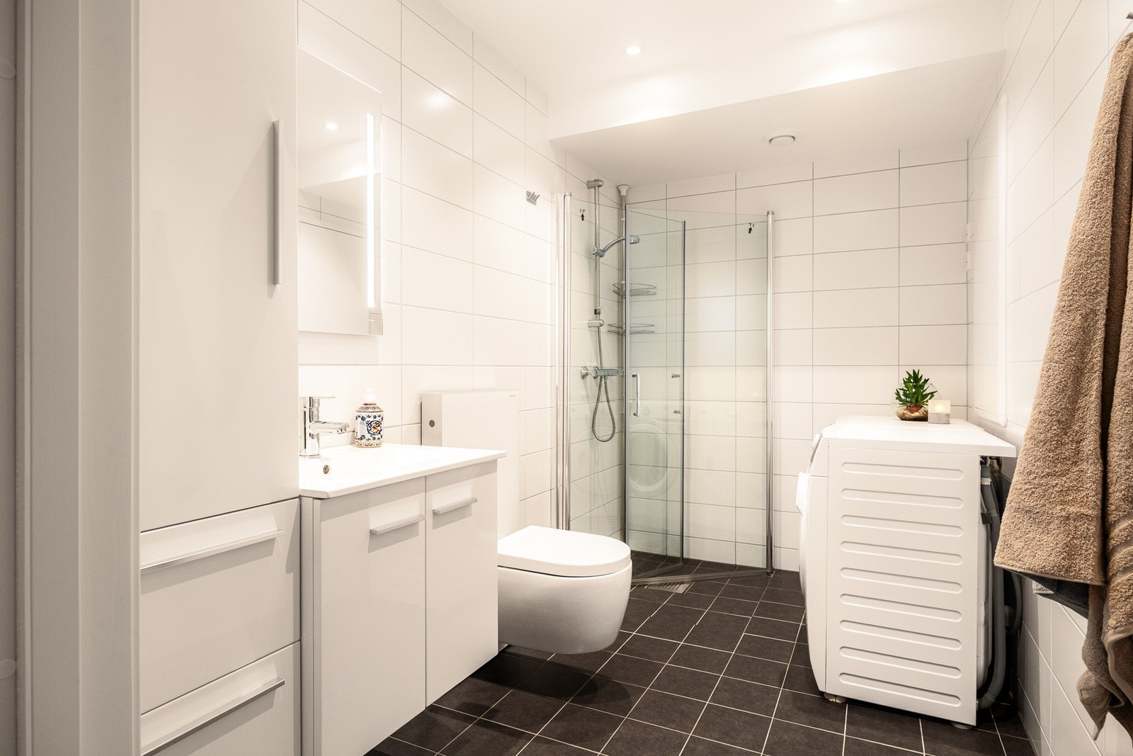 Flislagt baderom fra 2022 med moderne og funksjonelle løsninger, elektrisk gulvvarme og flislagte vegger som gir et slitesterkt og lettstelt uttrykk. Galleribilde