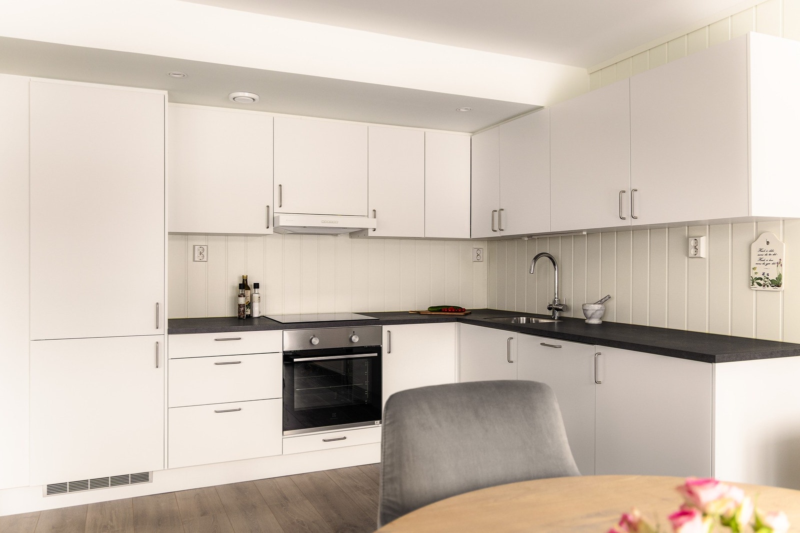 Kjøkkenet ligger i åpen løsning mot stuen og har en moderne innredning fra byggeåret 2022 med hvite, slette fronter og laminert benkeplate. Galleribilde