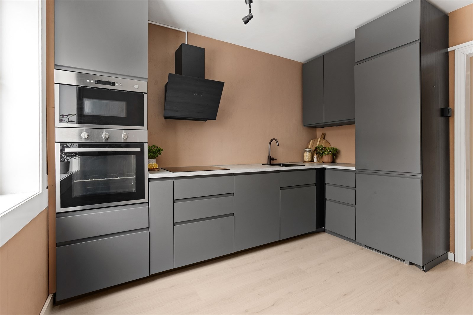 Kjøkkenet har en stilren innredning med mørke, slette fronter og integrerte hvitevarer. Galleribilde