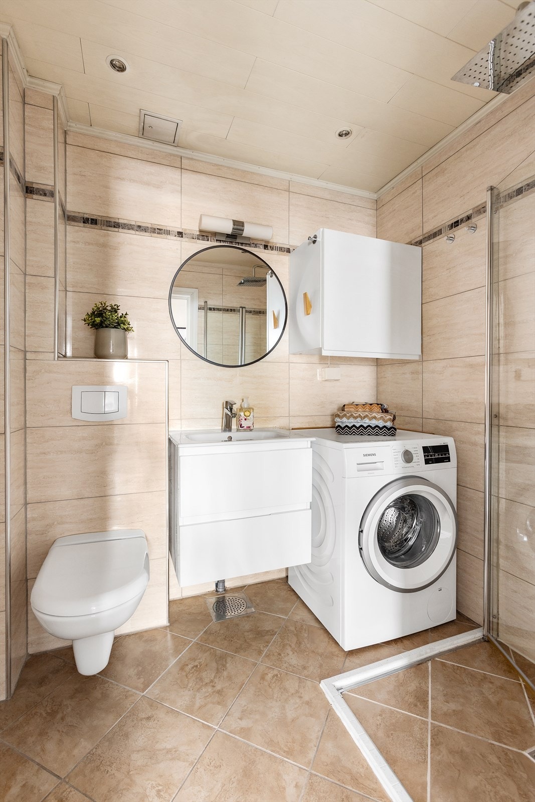 Badet er helfliset og utstyrt med vegghengt toalett og et praktisk dusjhjørne. Galleribilde