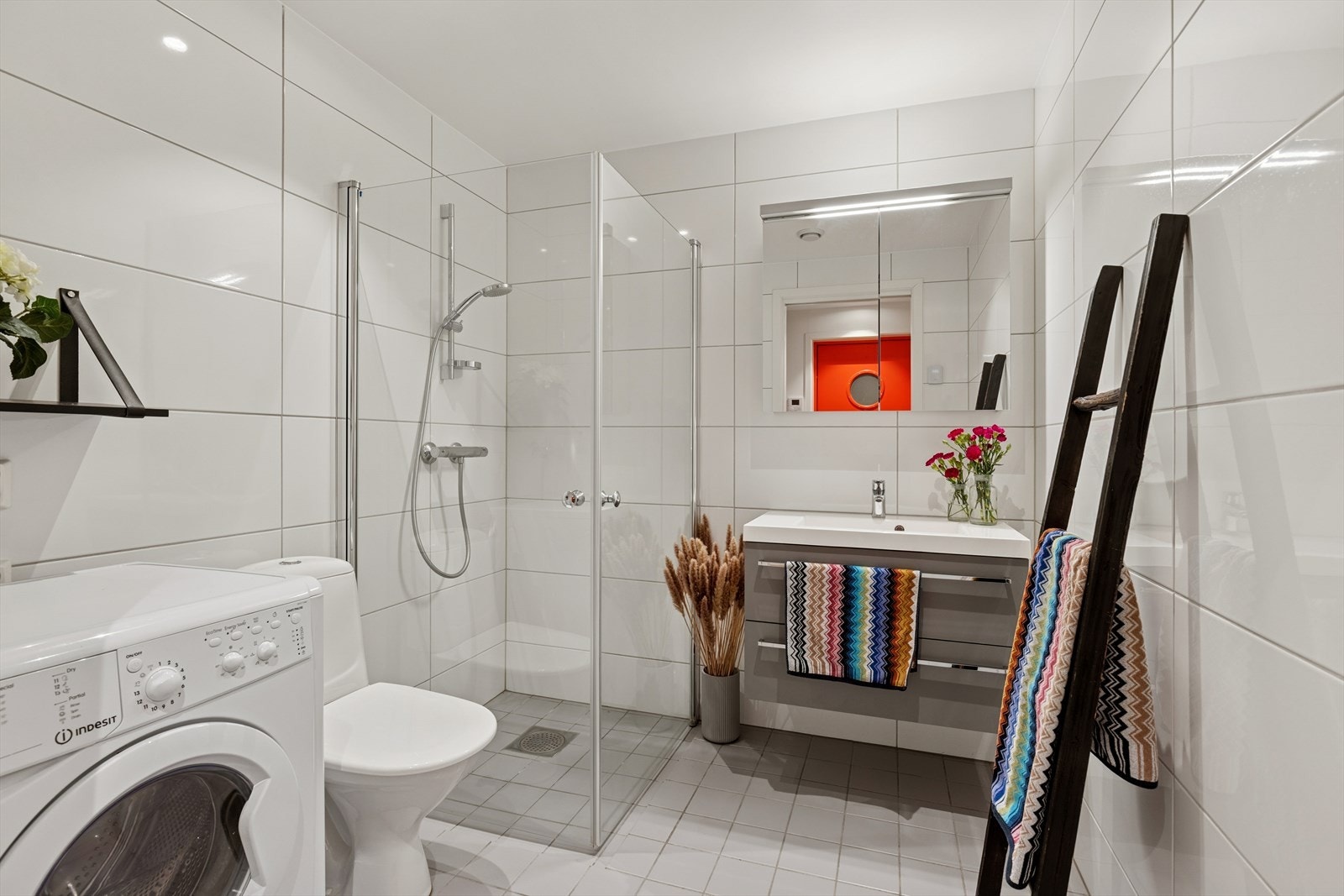 Bad som inneholder dusj hjørne, servant med skapplass, wc, speilskap og opplegg for vaskemaskin Galleribilde