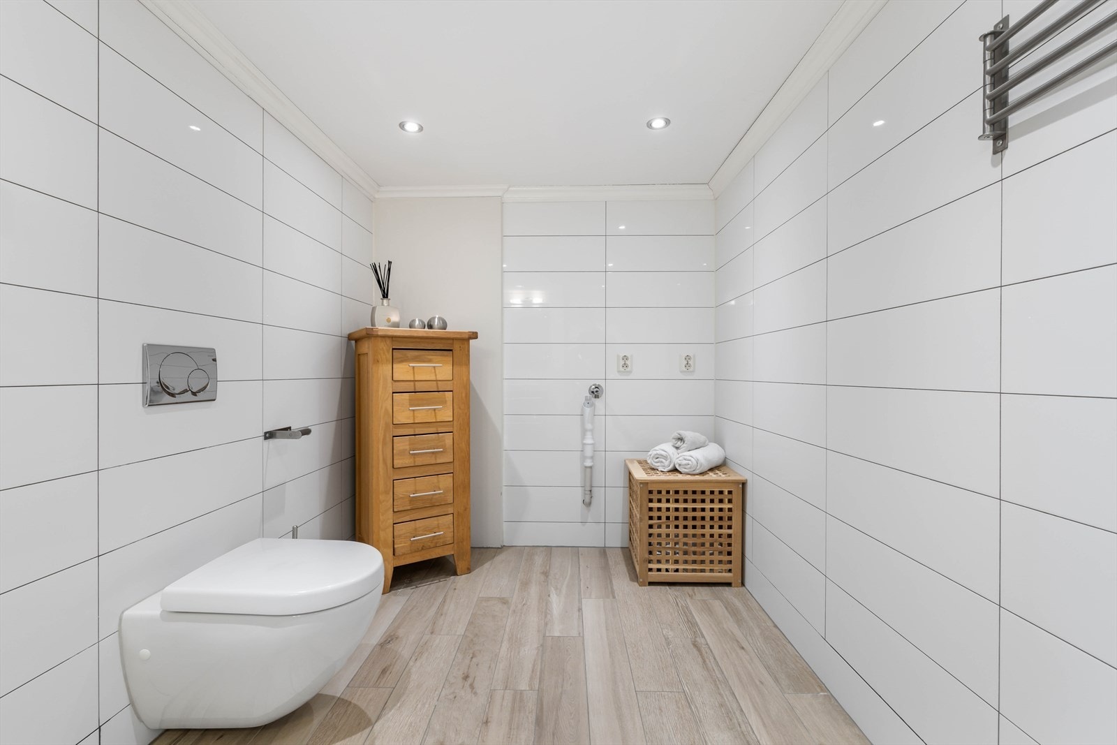 Badet er innredet med veggmontert toalett, dusjhjørne med glassveg, opplegg for vaskemaskin og innredning med nedfelt servant Galleribilde