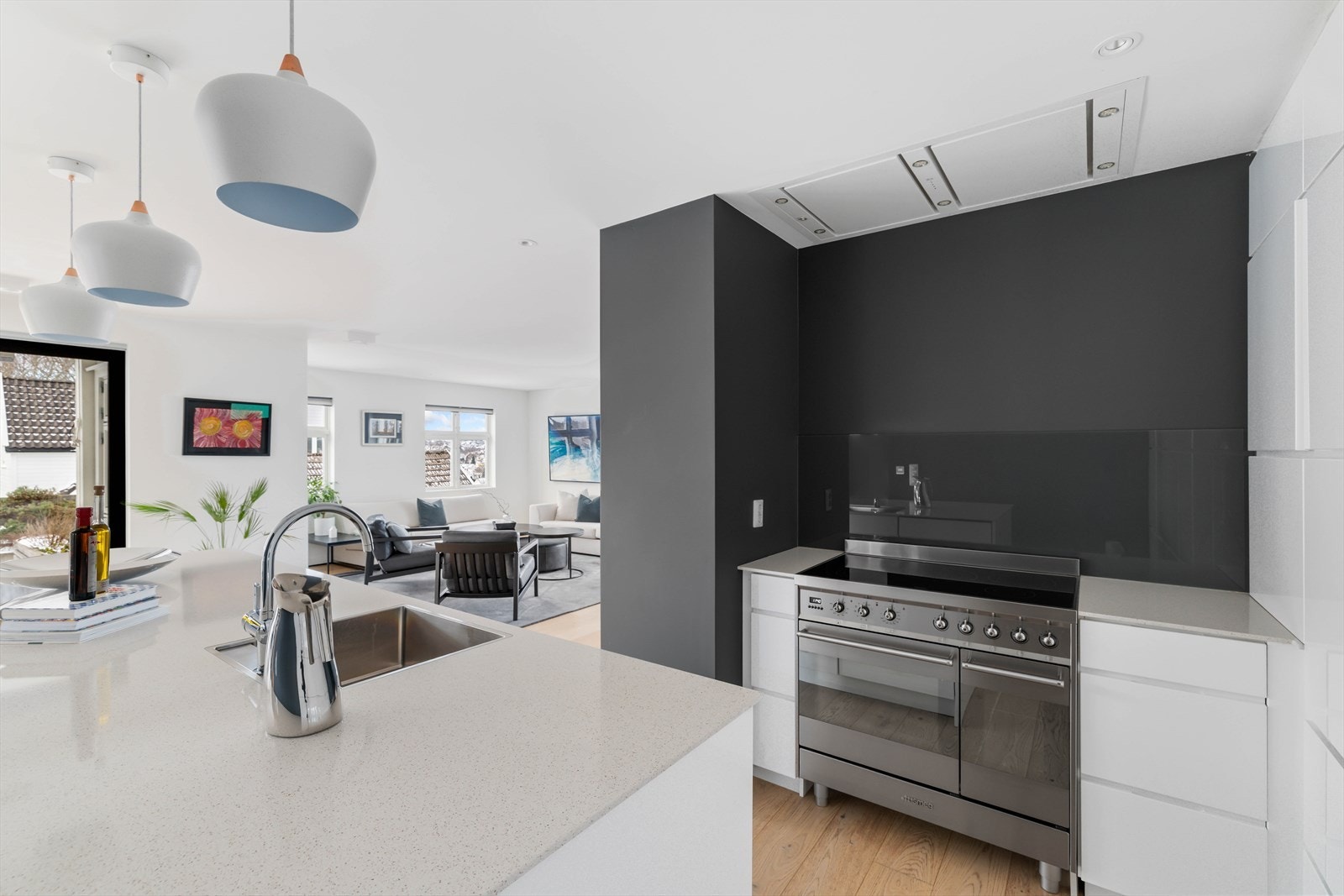 Rålekkert kjøkken innredet med glatte fronter og benkeplate i stein Galleribilde