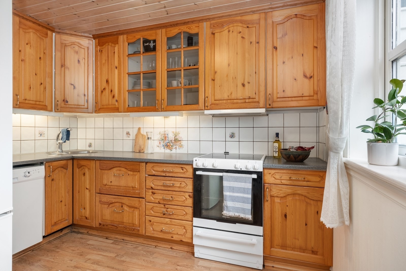 Kjøkkendelen har profilerte møbelfrontar av furu og benkeflate i laminat. Kvitevarer er frittståande. Galleribilde