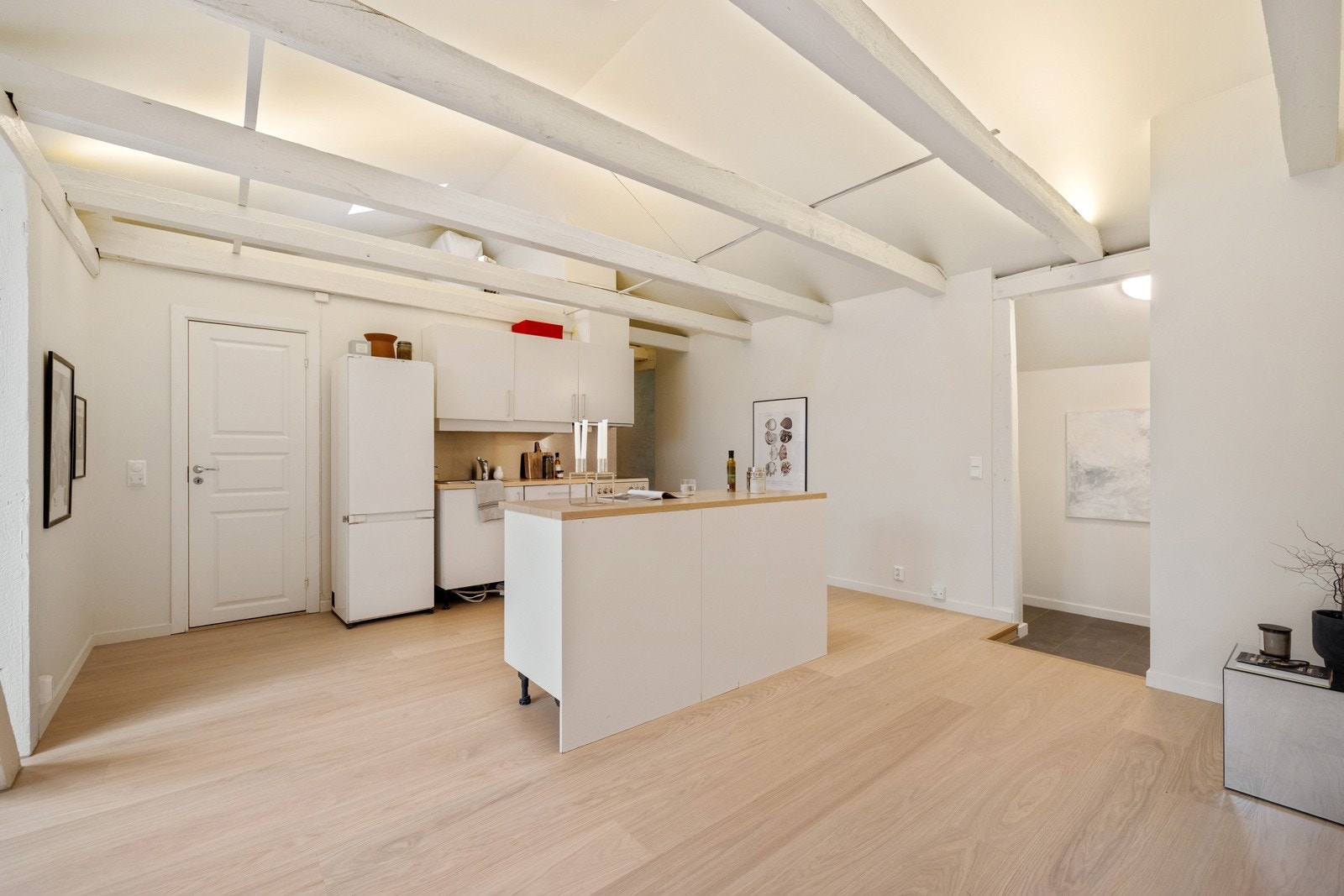 HTH-kjøkkeninnredning med glatte hvite fronter og benkeplate med nedfelt vaskekum i børstet stål. Galleribilde