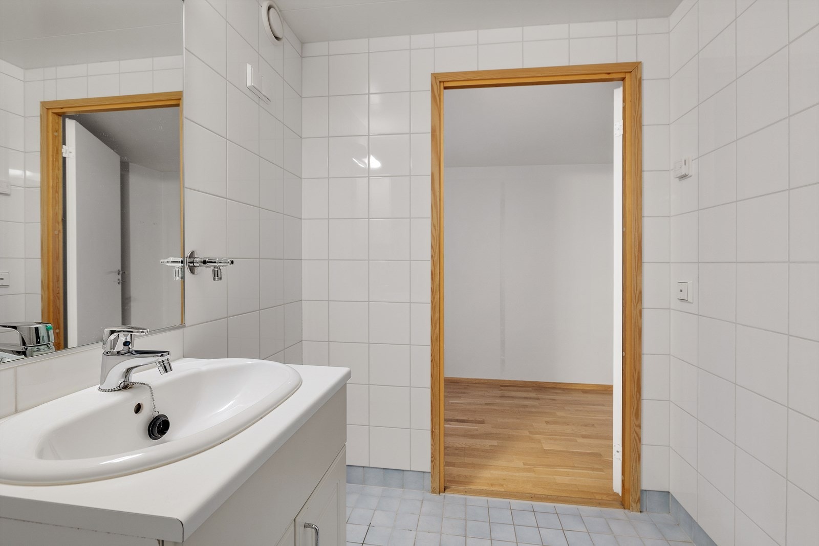 Installasjoner med servant på underskap og speil med belysning over, gulvstående toalett og dusjhjørne med glassdører. Galleribilde