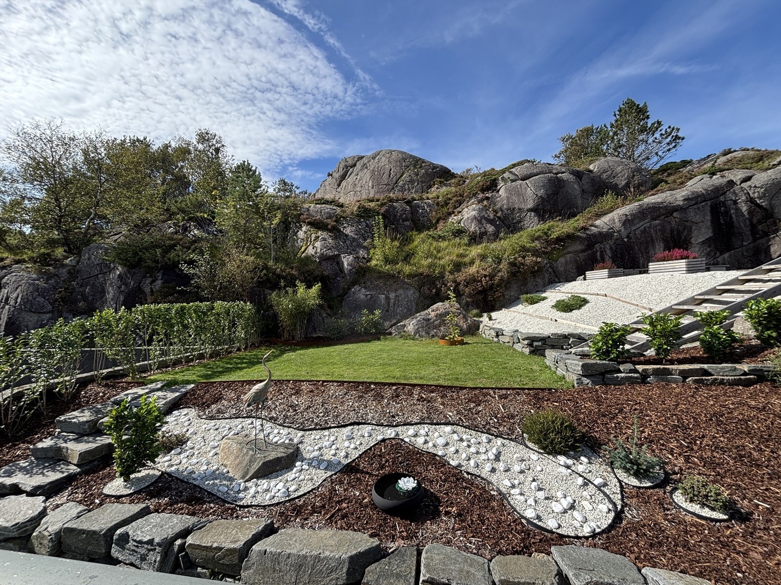 På baksiden av eiendommen bys det på et nydelig opparbeidet uteområde med terrassert hage, dekorative steinbed og lune naturmurer mot fjellet. Her får du et skjermet og solrikt uterom som krever lite vedlikehold - perfekt for rolige dager ute. Galleribilde