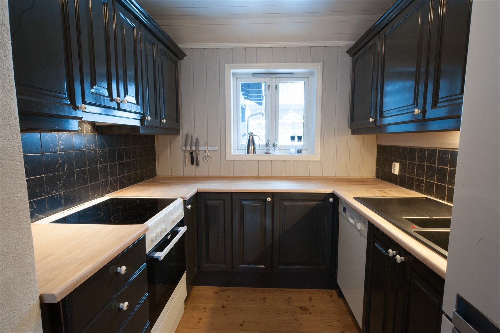 Kjøkkenet har en innredning i heltre med profilerte fronter og plass for frittstående hvitevarer. Galleribilde