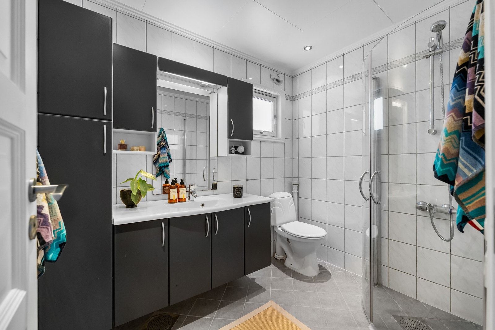 Helfliset baderom med elektriske varmekabler i gulvet. Badet har baderomsinnredning med servant, dusjhjørne med innfellbare dører, gulvstående wc Galleribilde