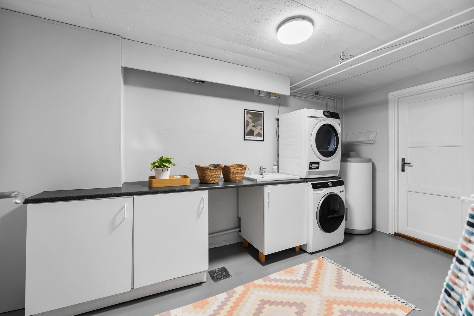 Praktisk vaskerom i underetasjen med opplegg til vaskemaskin og tørketrommel. Praktisk benkeplate med skap er satt inn. Varmtvannsbereder på 200 liter er plassert i dette rommet Galleribilde