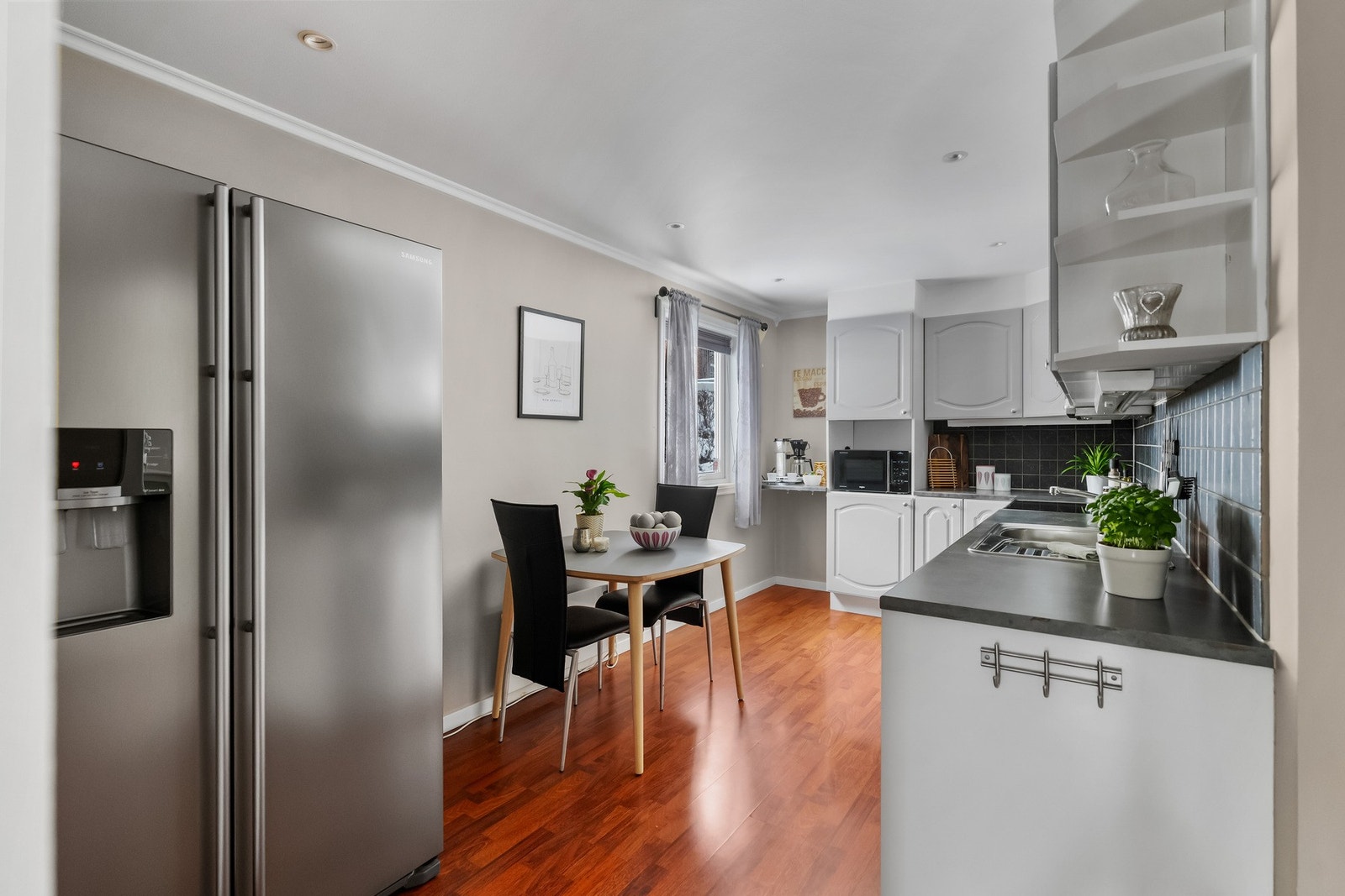 Kjøkkeninnredning med malte fronter, laminat benkeplate, oppvaskkum, ventilator og opplegg for
oppvaskmaskin. Fliser mellom overskap og benkeplate Galleribilde