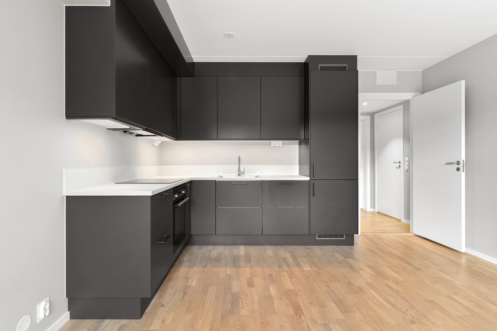 Stilren og moderne kjøkkeninnredning fra Sigdal med mørke fronter. Det funksjonelle L-formede designet utnytter plassen godt, og sørger for rikelig med benke- og skapplass. Kjøkkenet er utstyrt med integrerte hvitevarer fra Siemens, som induksjonstopp, ko Galleribilde