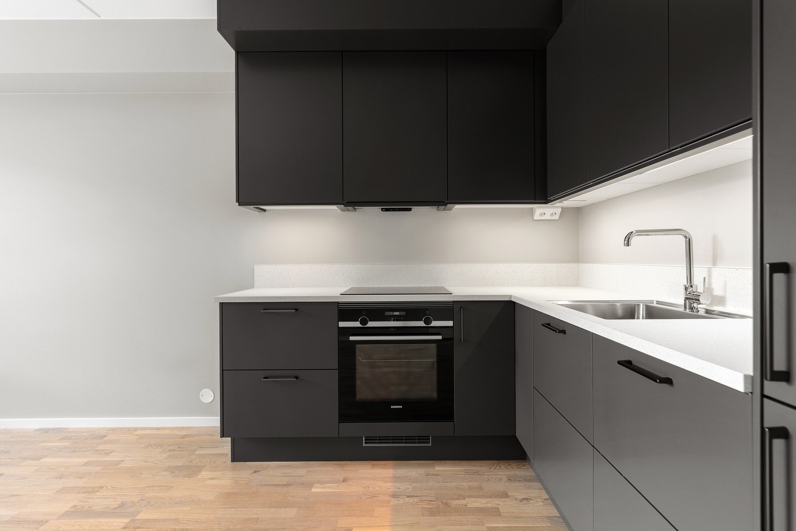 Stilren og moderne kjøkkeninnredning fra Sigdal med mørke fronter. Det funksjonelle L-formede designet utnytter plassen godt, og sørger for rikelig med benke- og skapplass. Kjøkkenet er utstyrt med integrerte hvitevarer fra Siemens, som induksjonstopp, ko Galleribilde