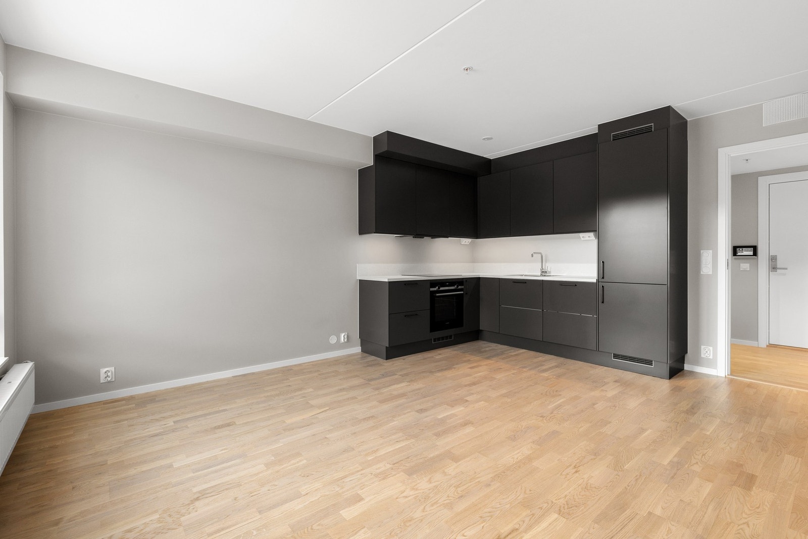 Stilren og moderne kjøkkeninnredning fra Sigdal med mørke fronter. Det funksjonelle L-formede designet utnytter plassen godt, og sørger for rikelig med benke- og skapplass. Kjøkkenet er utstyrt med integrerte hvitevarer fra Siemens, som induksjonstopp, ko Galleribilde