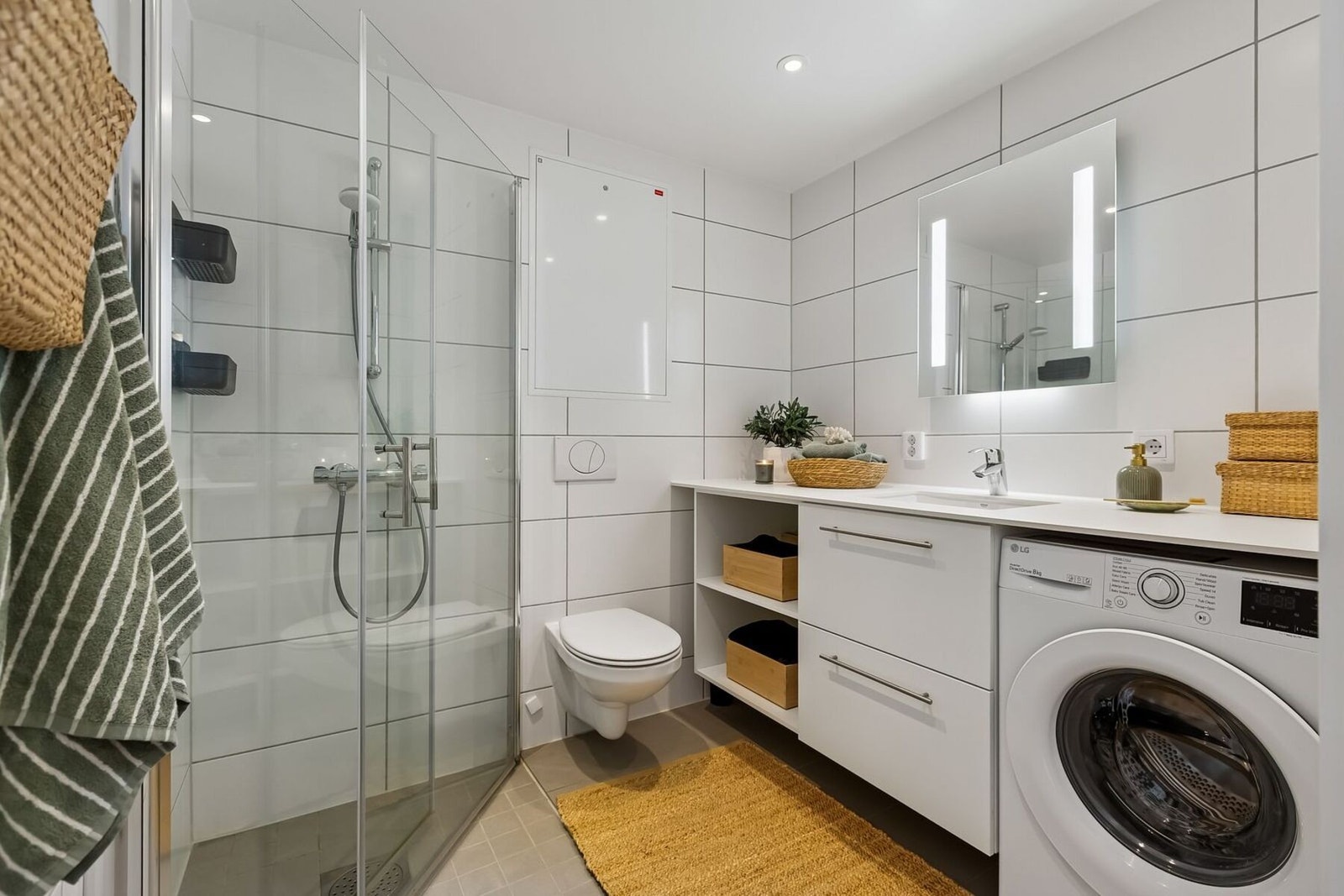 Pent flislagt baderom på gode 4,5 kvadratmeter med praktisk opplegg til vaskemaskin og gjennomført benkeplate over. Galleribilde