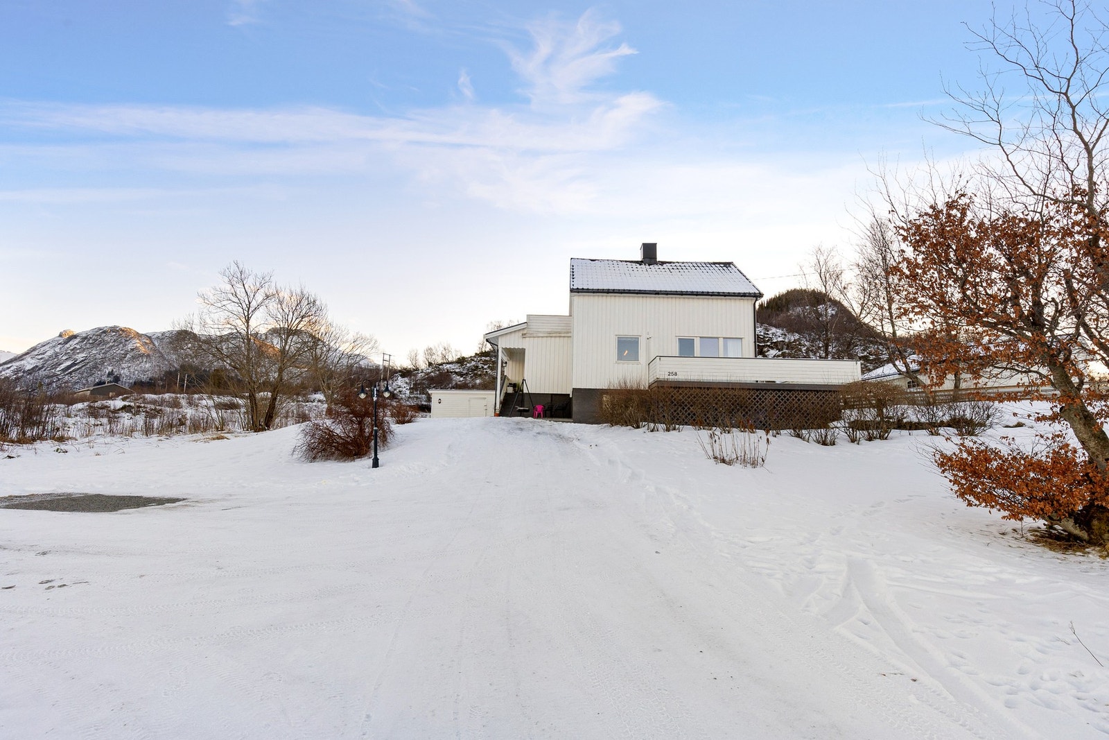 Tomten er pent opparbeidet med plen, trær, hekk og en gruset gårdsplass for parkering. Galleribilde