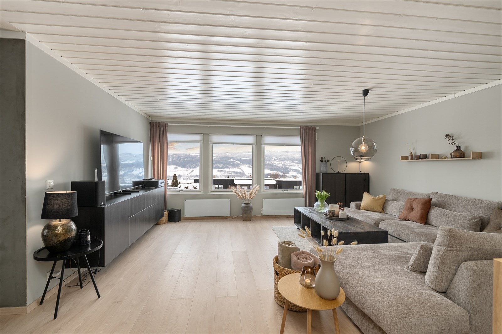 Det er et hyggelig og sosialt oppholdsrom i boligen med lune og tidløse fargetoner som harmonerer godt sammen og skaper en fin flyt over i spisestue, lounge og kjøkken. Galleribilde