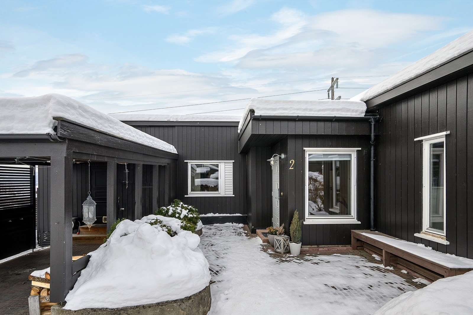 Det er en forholdsvis skjermet gårdsplass med en lun og fin uteplass der morgenkaffen kan nytes. Fra carporten er det direkte inngang til kjøkkent. Galleribilde