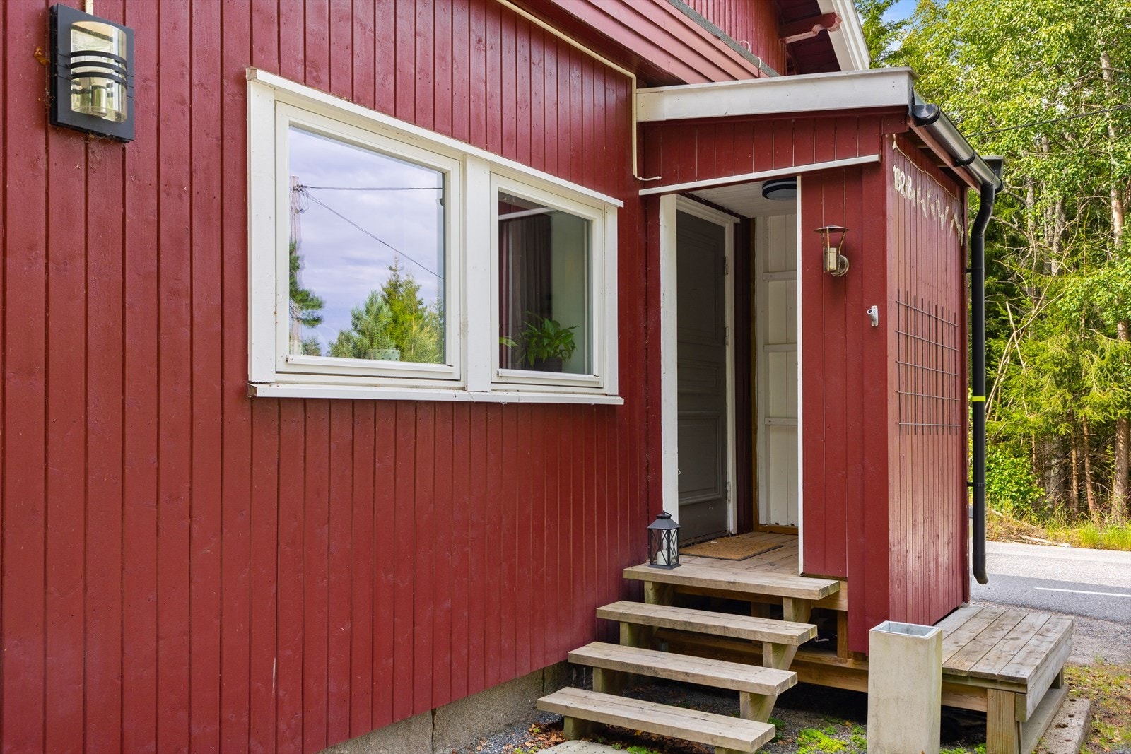 Adkomst til boligens 1. etasje fra gruset gårsdplass og trapp opp til inngangspartiet. Galleribilde