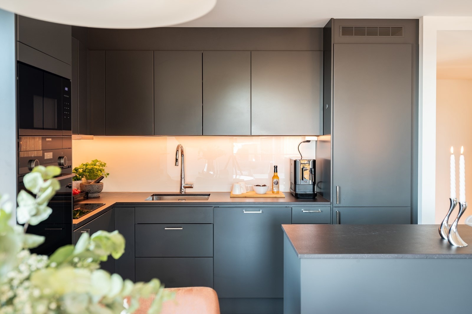 Det er blant annet gjort tilvalg på kjøkkenet med Dekton benkeplate, kjøkkenøy, kjøkkenkran og glass bak benkeplate. Kjøkkenet er levert av kvalitetsleverandøren Drømmekjøkken og innehar rikelig med skap- og benkeplass. Galleribilde