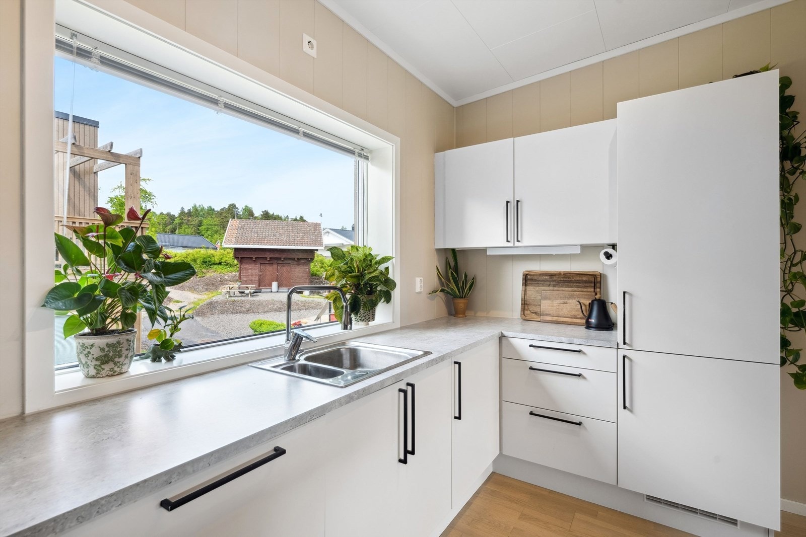 Klassisk og elegant kjøkkeninnredning med hvite slette fronter og benkeplate av laminat. Galleribilde