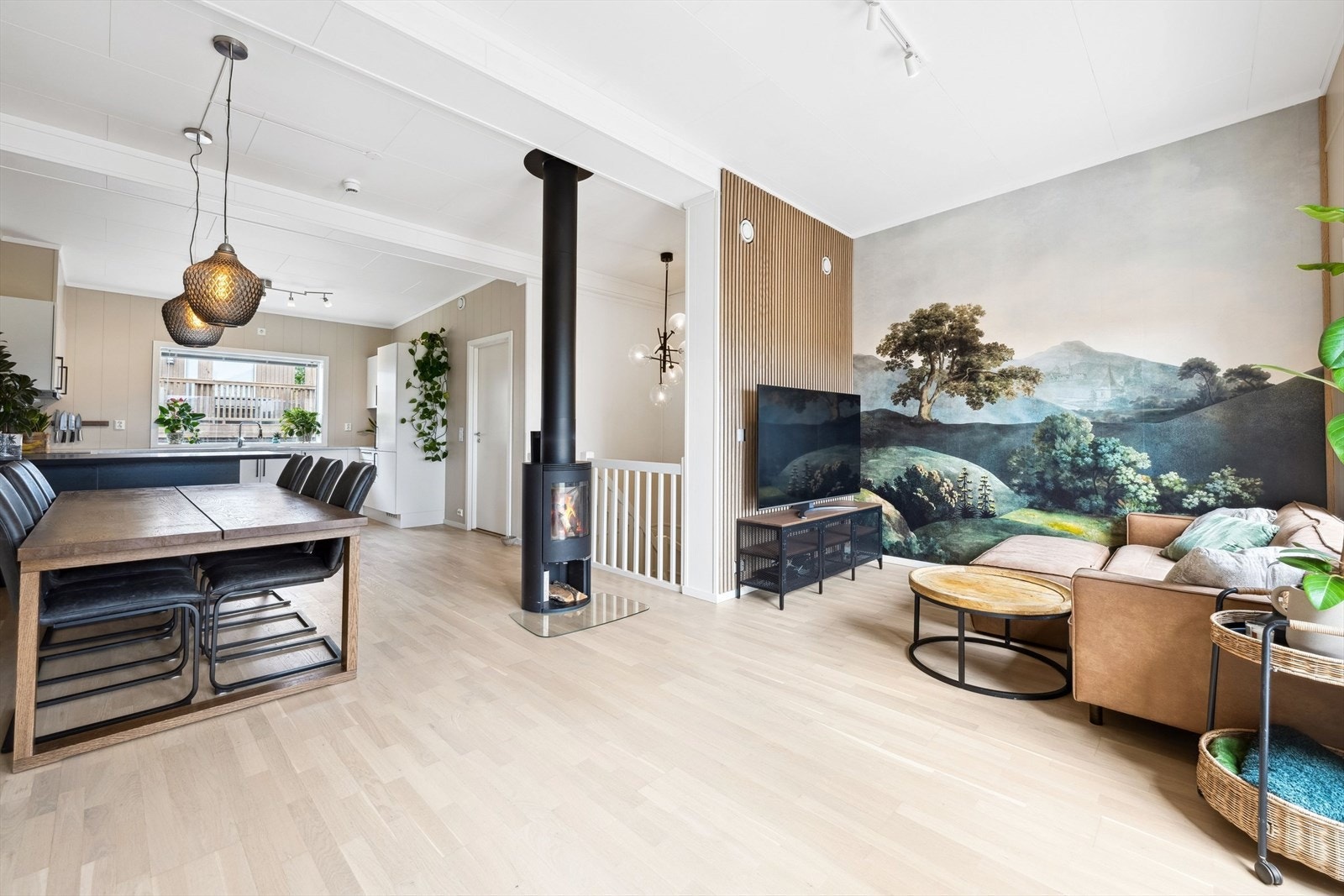 Kontrastveggen i stuen, med dekorativt tapet kombinert med elegante trespiler, skaper et blikkfang som tilfører rommet både dybde, varme og en moderne karakter. Galleribilde