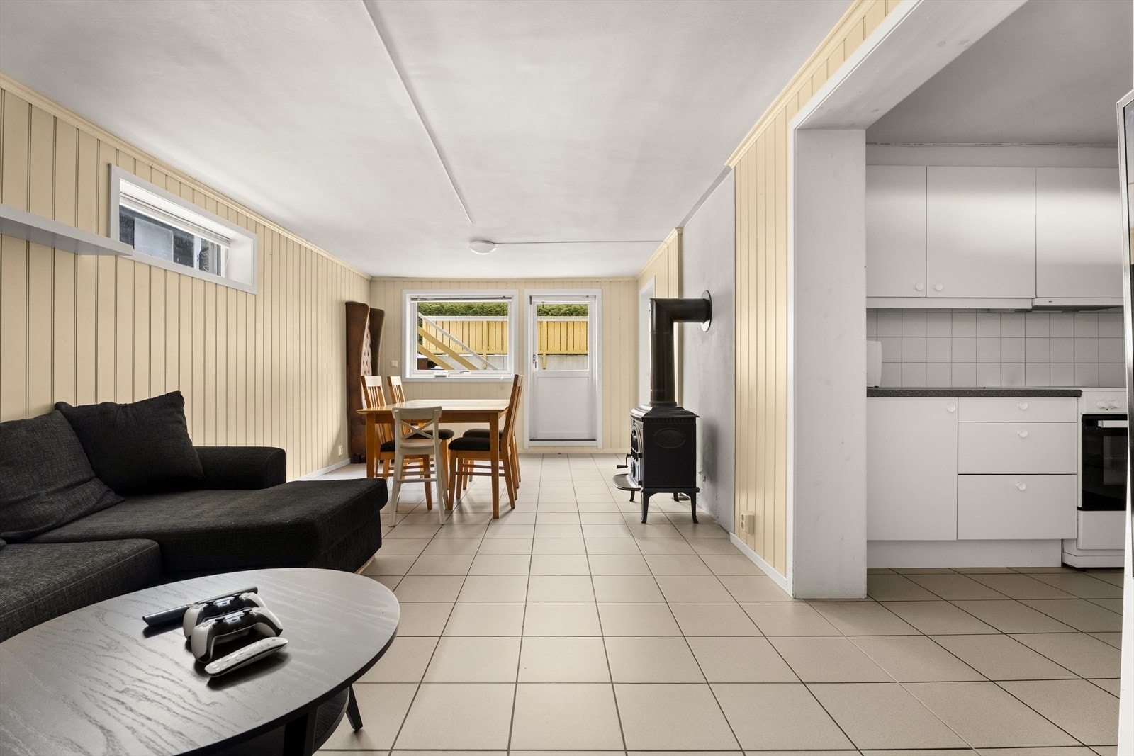 Stuen i kjelleren har fliser på gulvet og en vedovn som gir god varme. Galleribilde