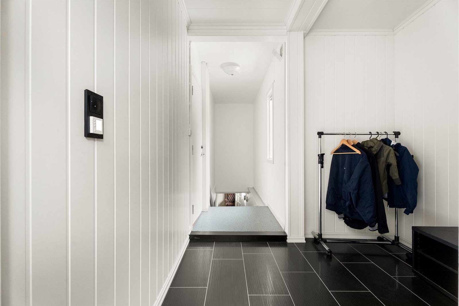 En malt tretrapp med belegg i trinnene leder ned til kjelleretasjen. Galleribilde