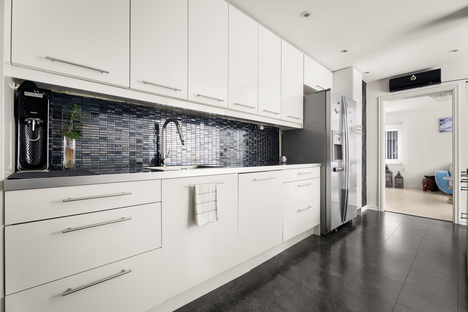 Det er fliser mellom laminert benkeplate og overskap, som beskytter veggen. Galleribilde