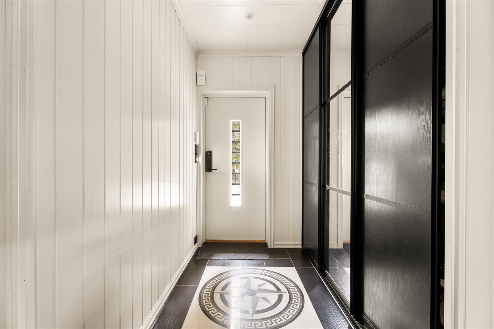 Den malte inngangsdøren har et vertikalt glassfelt som gir et hyggelig lysinnslipp. Galleribilde