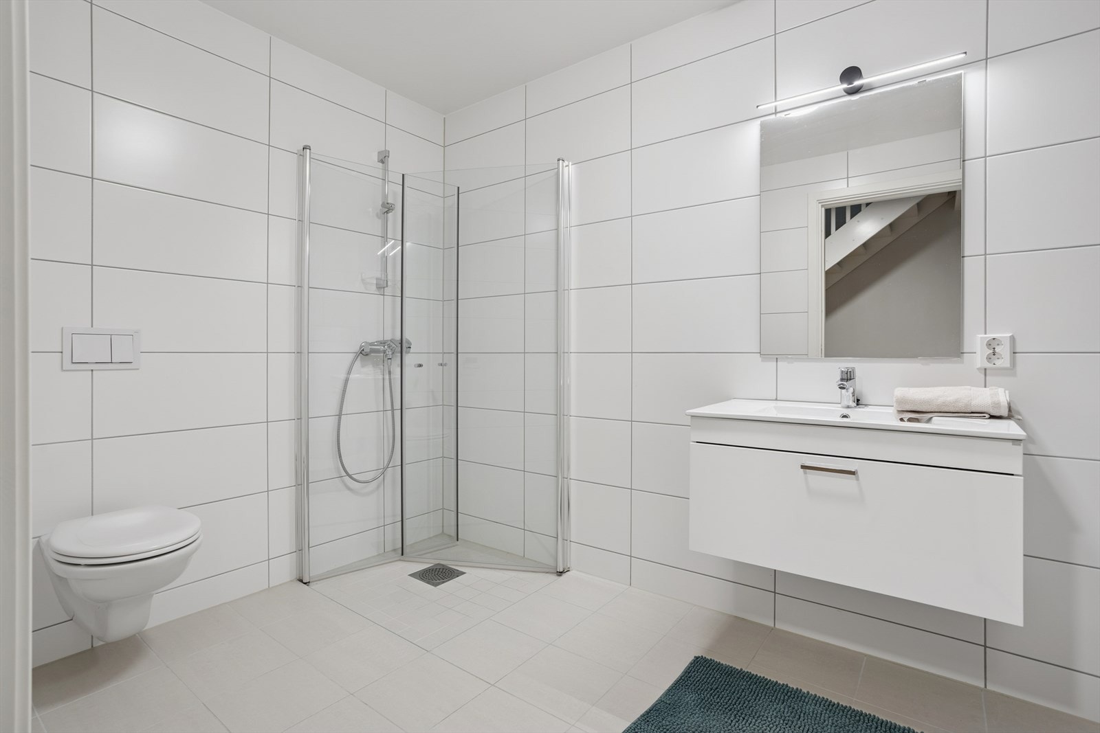 Badet i 1. etasje er lekkert og tidsriktig med fliser, dusjhjørne og vegghengt toalett. Praktisk løsning med opplegg for vaskemaskin og varme i gulvet Galleribilde