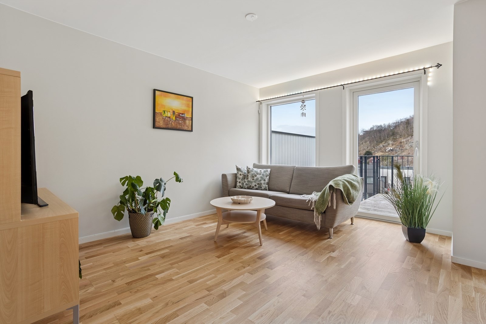 Lyst og romslig med store vindusflater og direkte utgang til altan fra sofakroken Galleribilde