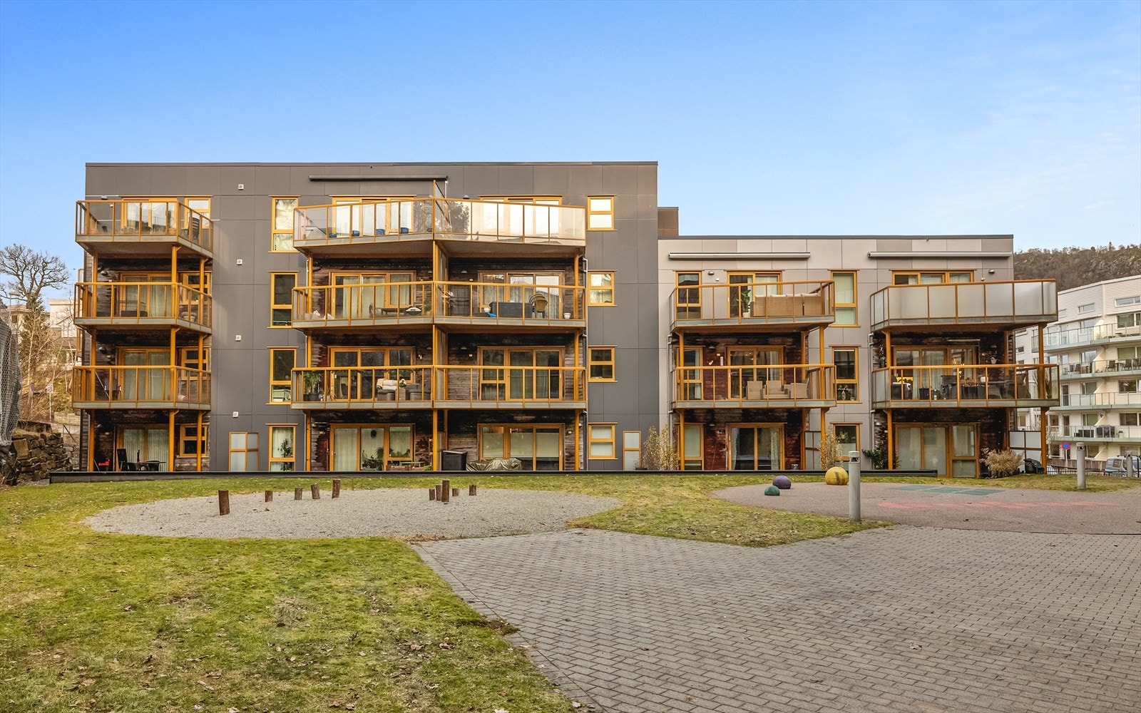 Fellesområdene er pent opparbeidet med plen, beplantning, hellelagte plasser og lekestativ. Galleribilde