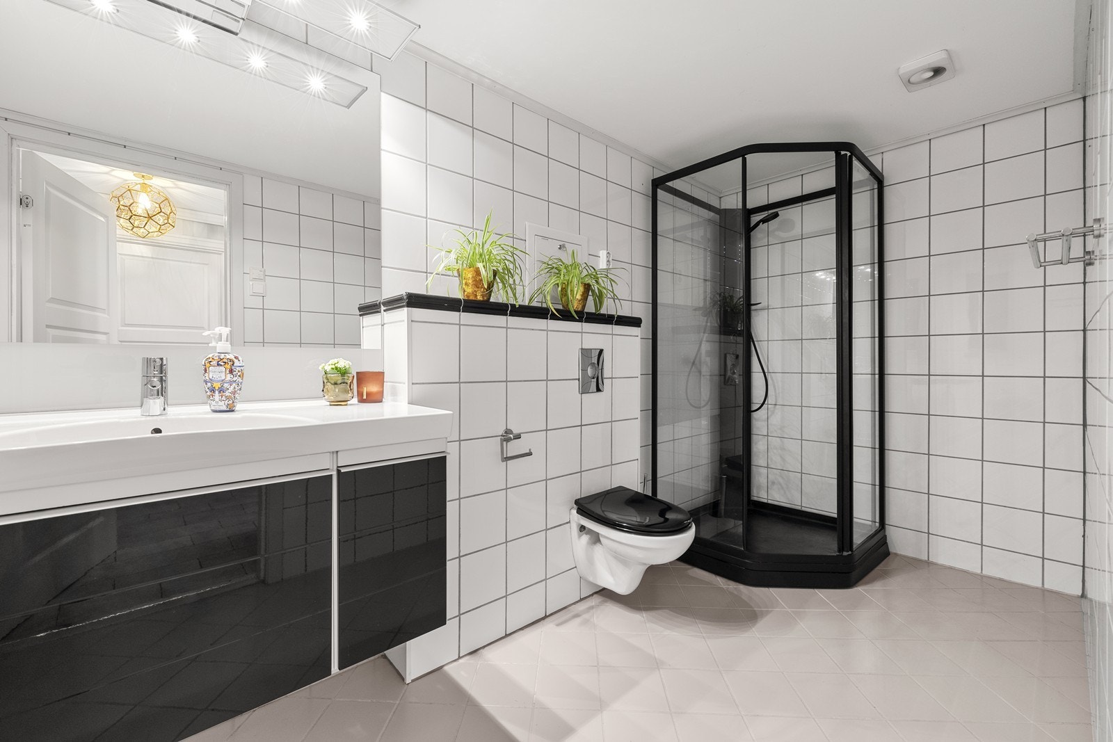 Badet er pent, flislagt med dusjkabinett og vegghengt toalett med innebygget sisterne. Galleribilde